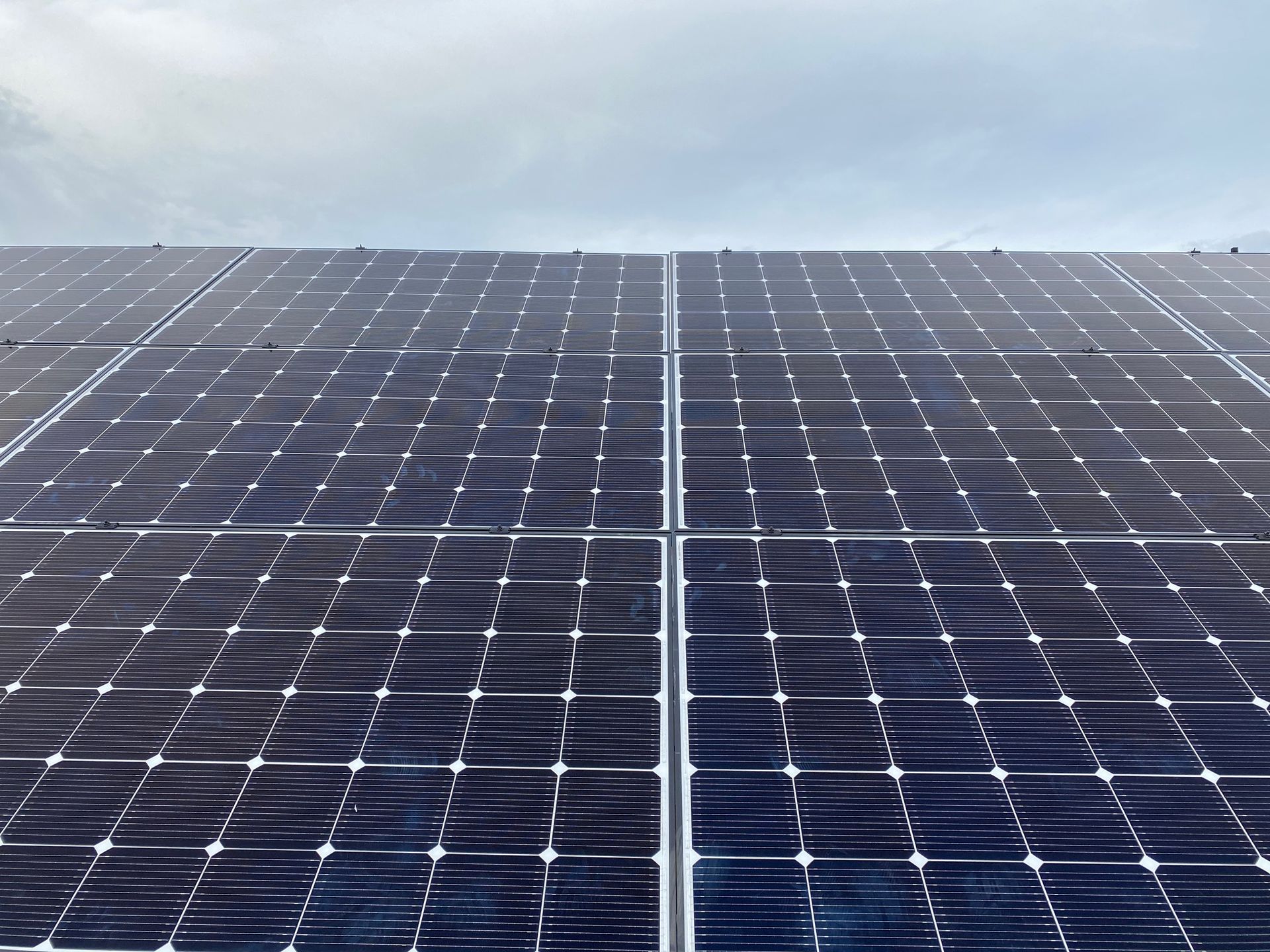 A row of solar panels against a cloudy sky