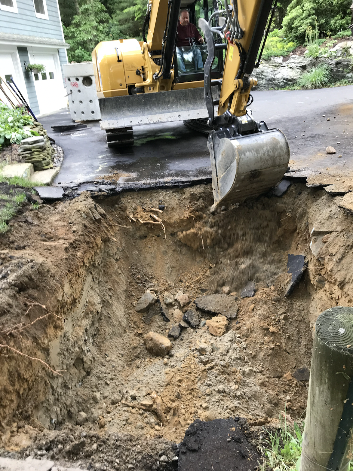 A bulldozer is digging a hole in the ground in front of a house.