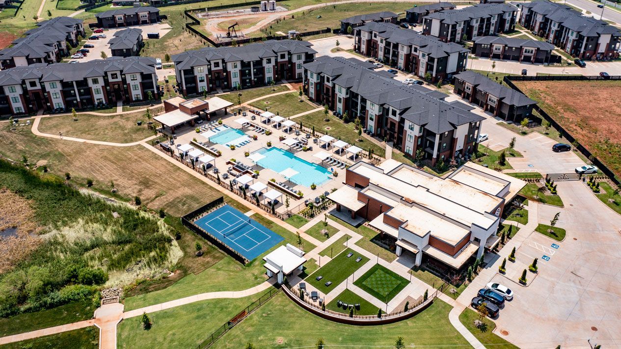 An aerial view of a large apartment complex with a swimming pool and court.