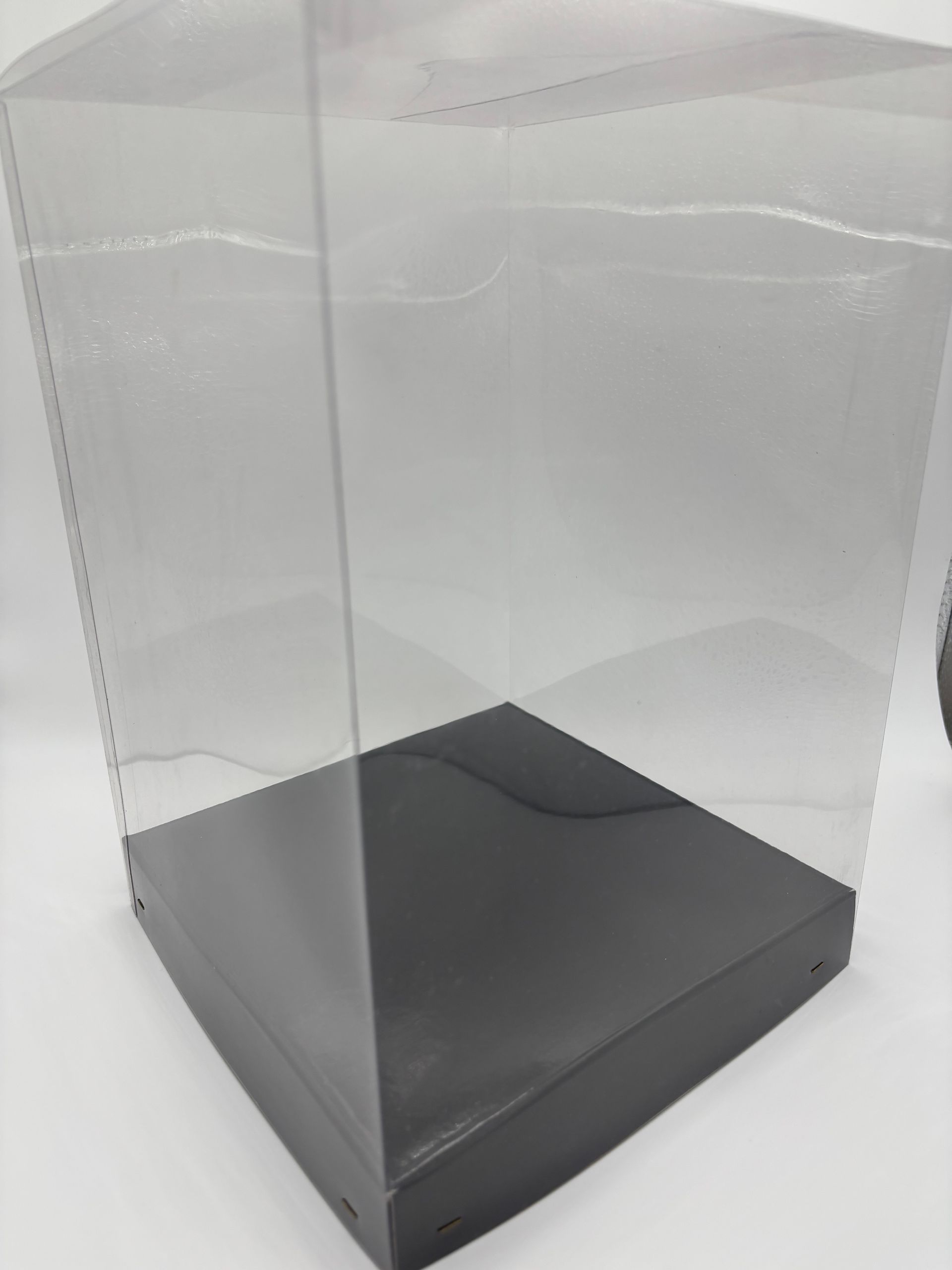 Vetrina in acrilico trasparente con base nera, su superficie bianca.