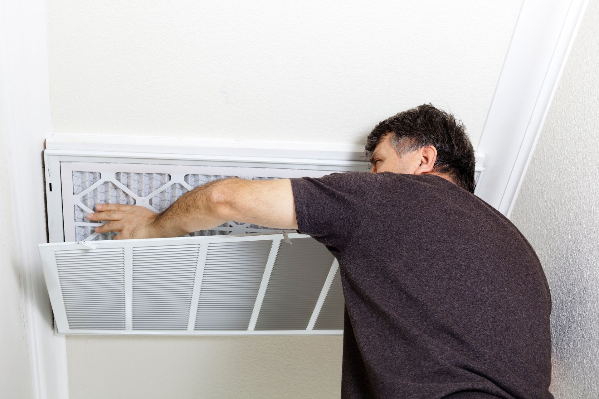 Technician installing a new air conditioner filter in a Cartersville home to improve energy efficien