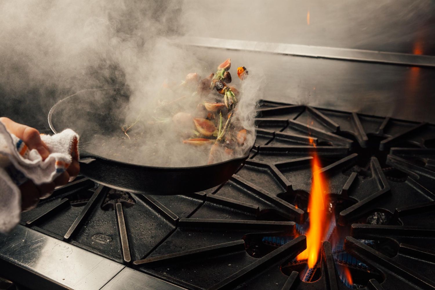 cropped-hand-tossing-vegetables-cooking-pan