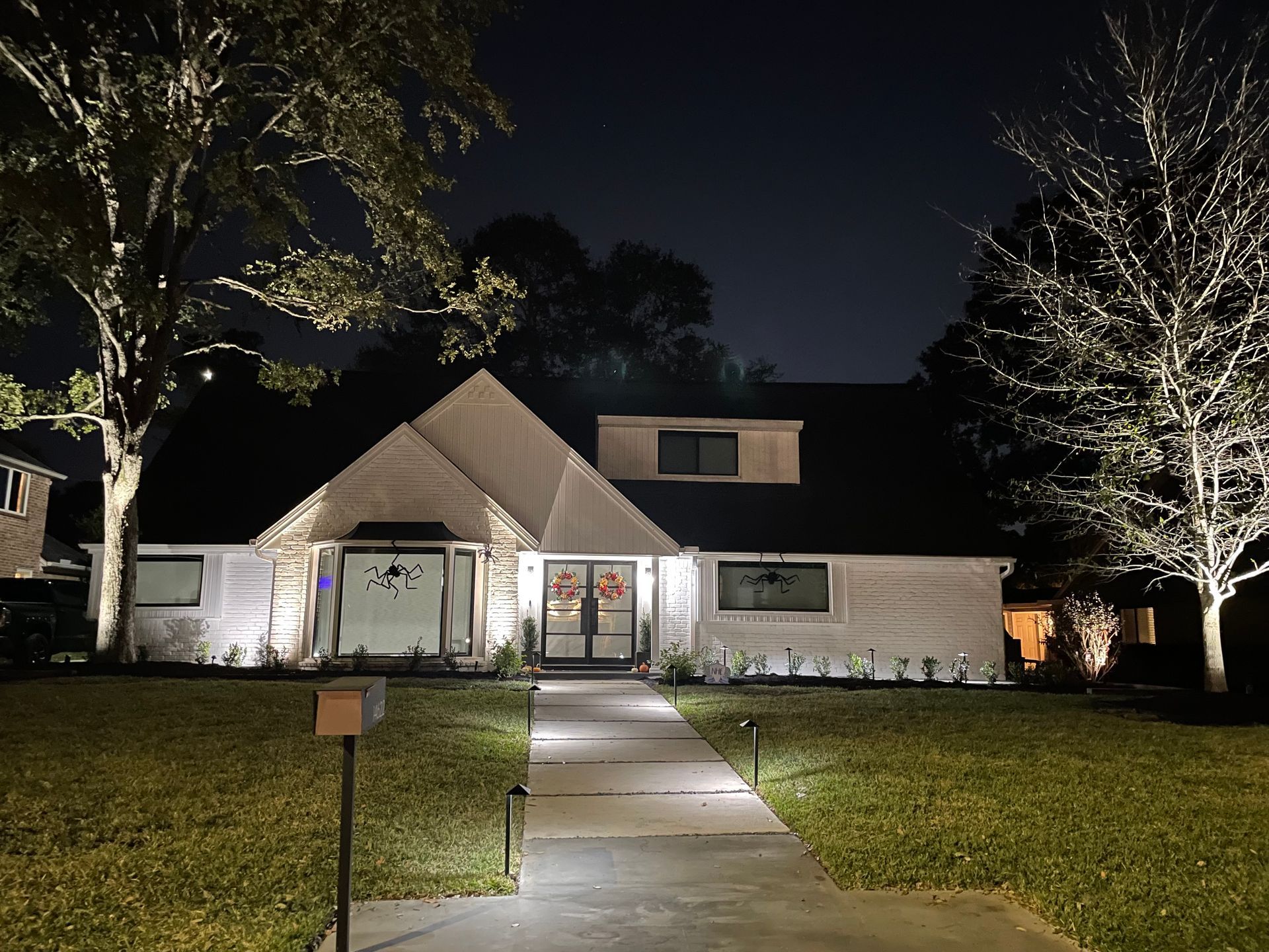 A white house with a black roof is lit up at night