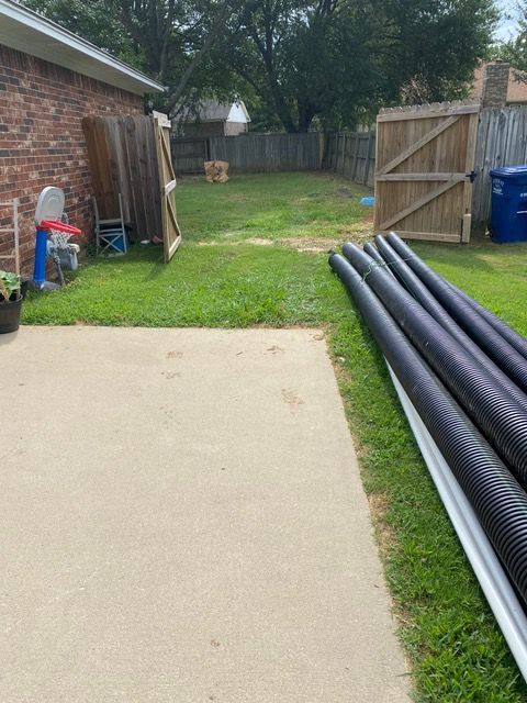 a bunch of pipes are laying on the grass in a backyard ready for a drainage solutions.