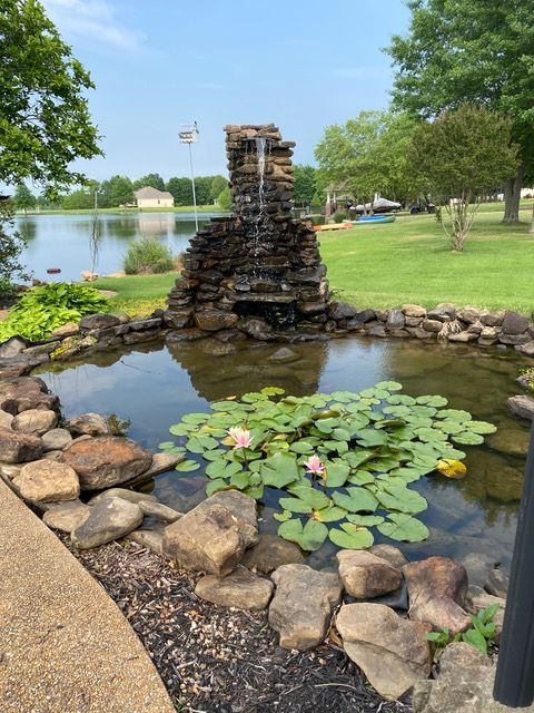 a pond with water lilies and a waterfall in the background