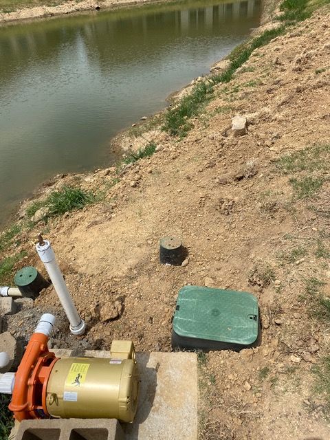 a pump is sitting in the dirt next to a body of water .