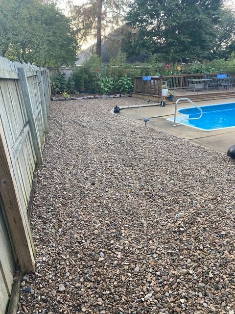 a fence surrounds a swimming pool in a backyard .