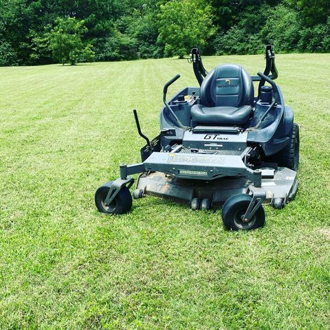 a lawn mower is sitting in the middle of a lush green field .
