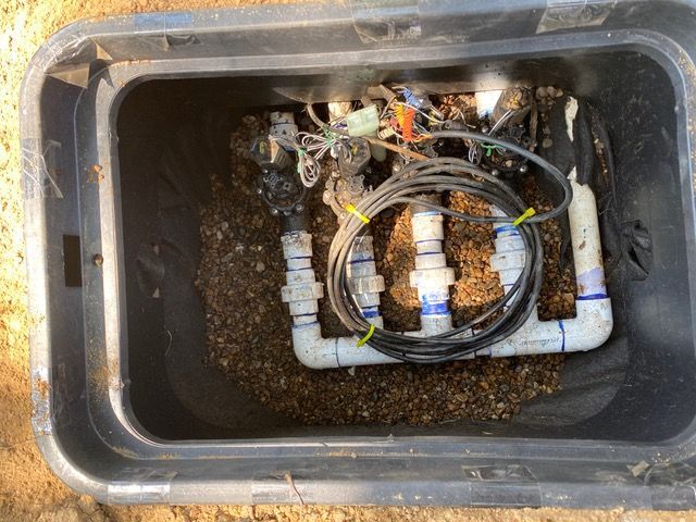 a black box filled with pipes and wires is sitting in the dirt ready for drainage solutions.