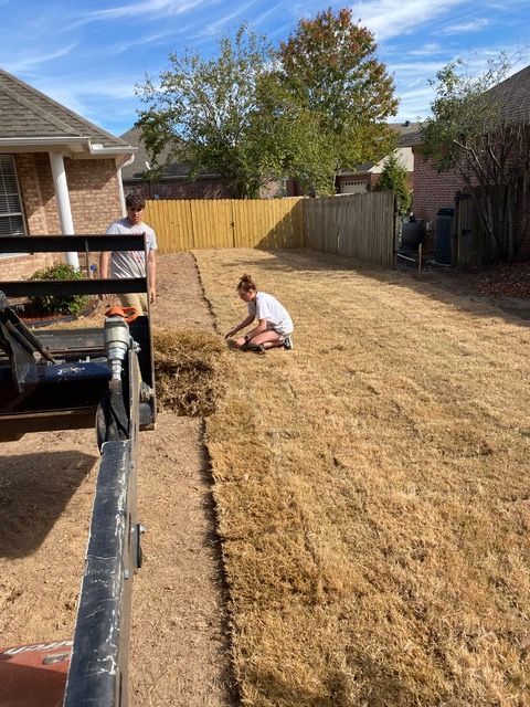 SouthernGrounds team are working on a lawn in a backyard.