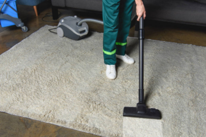 Cleaner vacuuming rug in living room.
