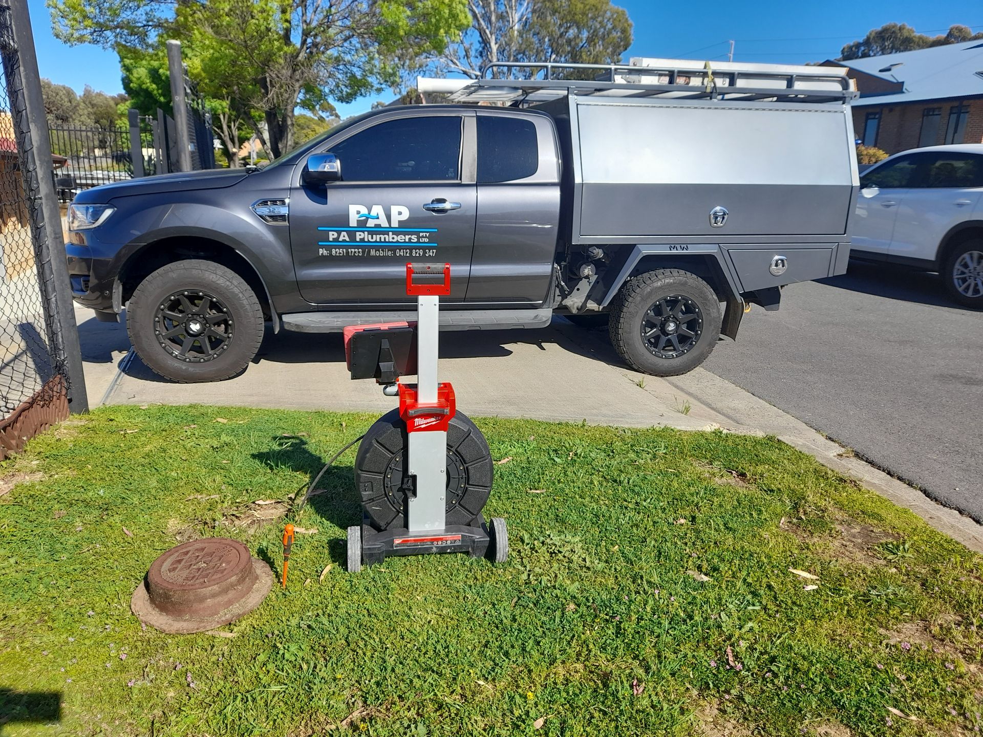 A truck is parked on the side of the road next to a lawn mower.