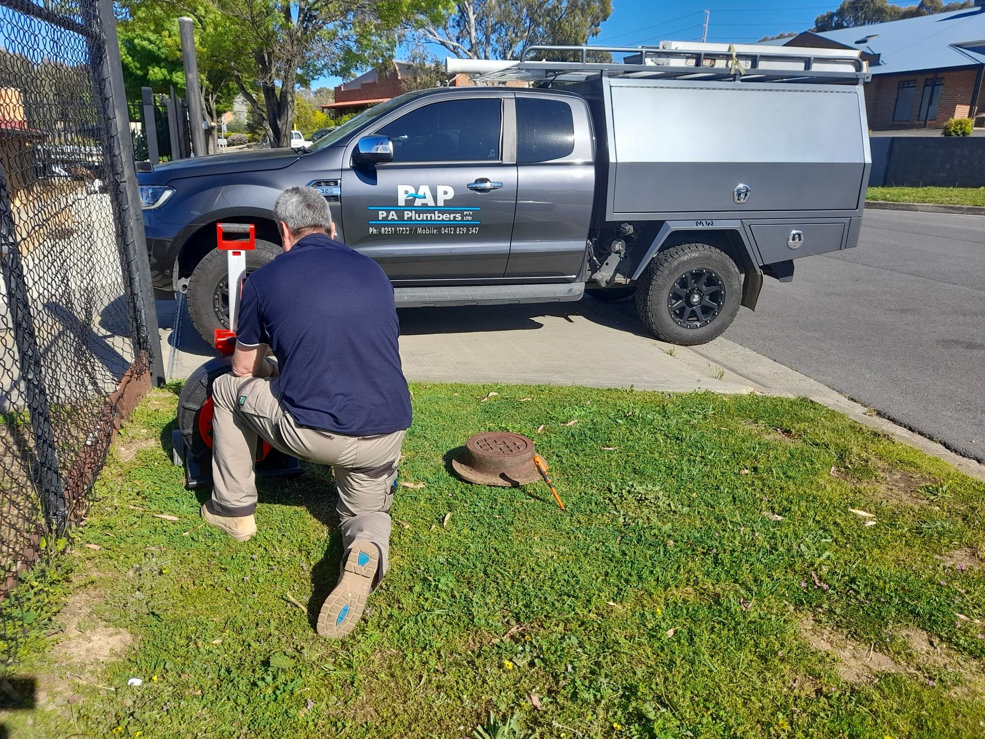 A man is kneeling in front of a truck that says pap on the side.