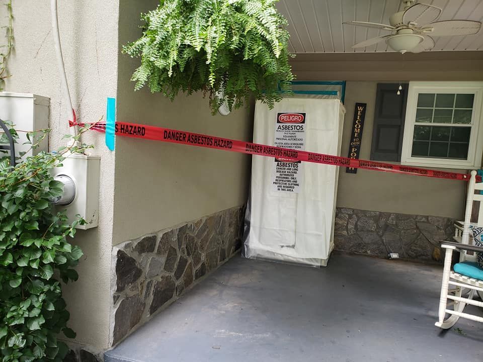 A rocking chair is on the porch of a house with a caution tape around the door