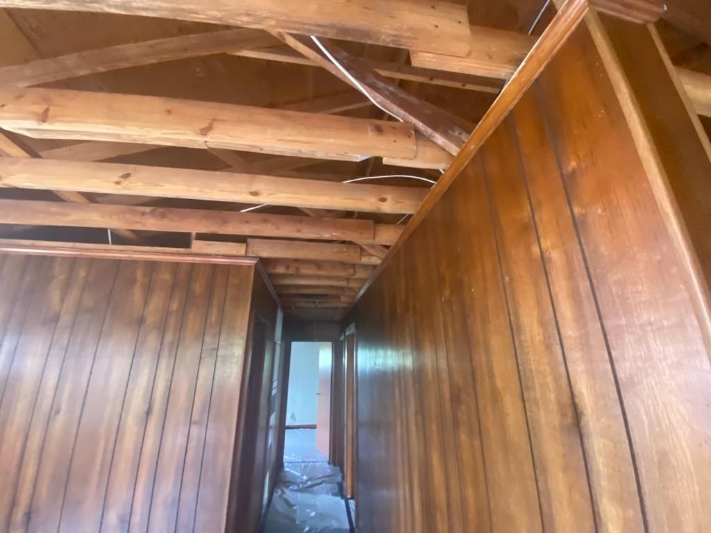 A hallway in a house with wood paneling and beams.