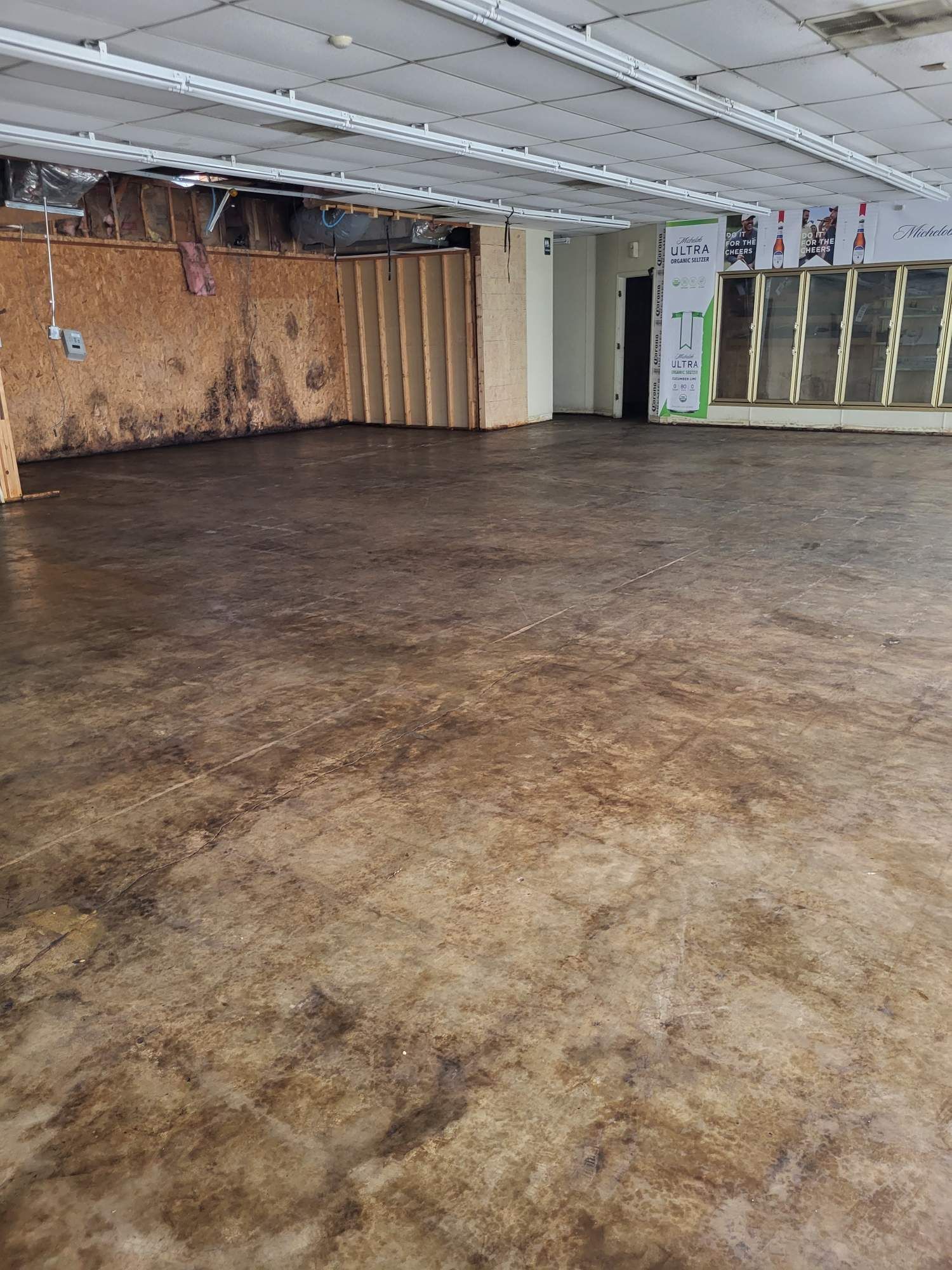 An empty room with a concrete floor and a wooden wall.