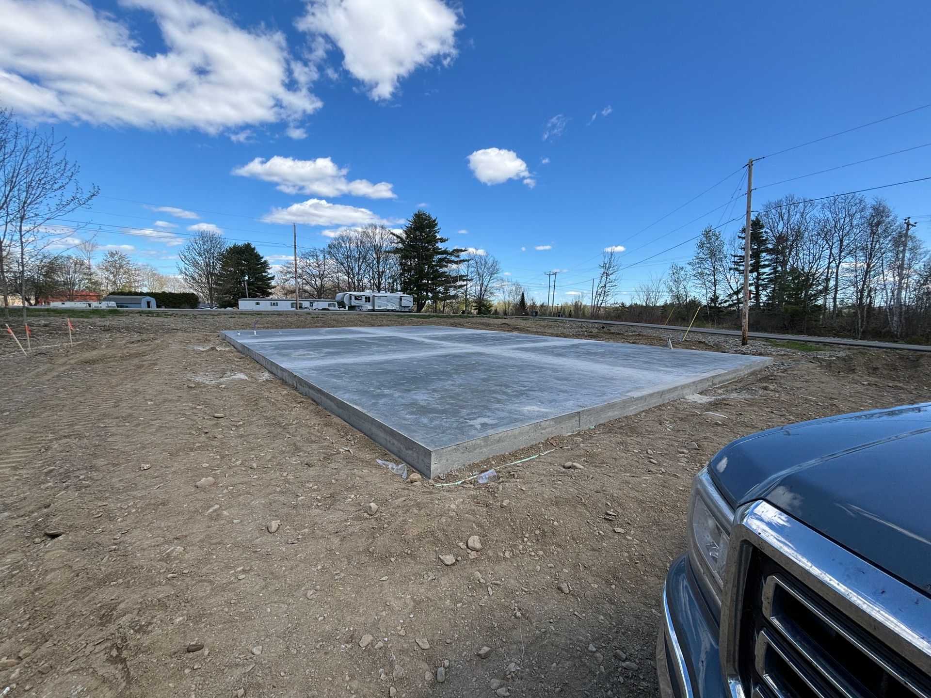 A truck is parked next to a concrete slab in a dirt field.
