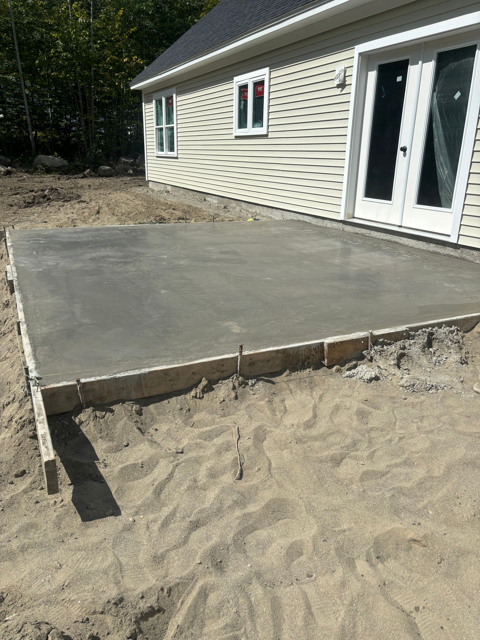 A concrete patio is being built in front of a house.