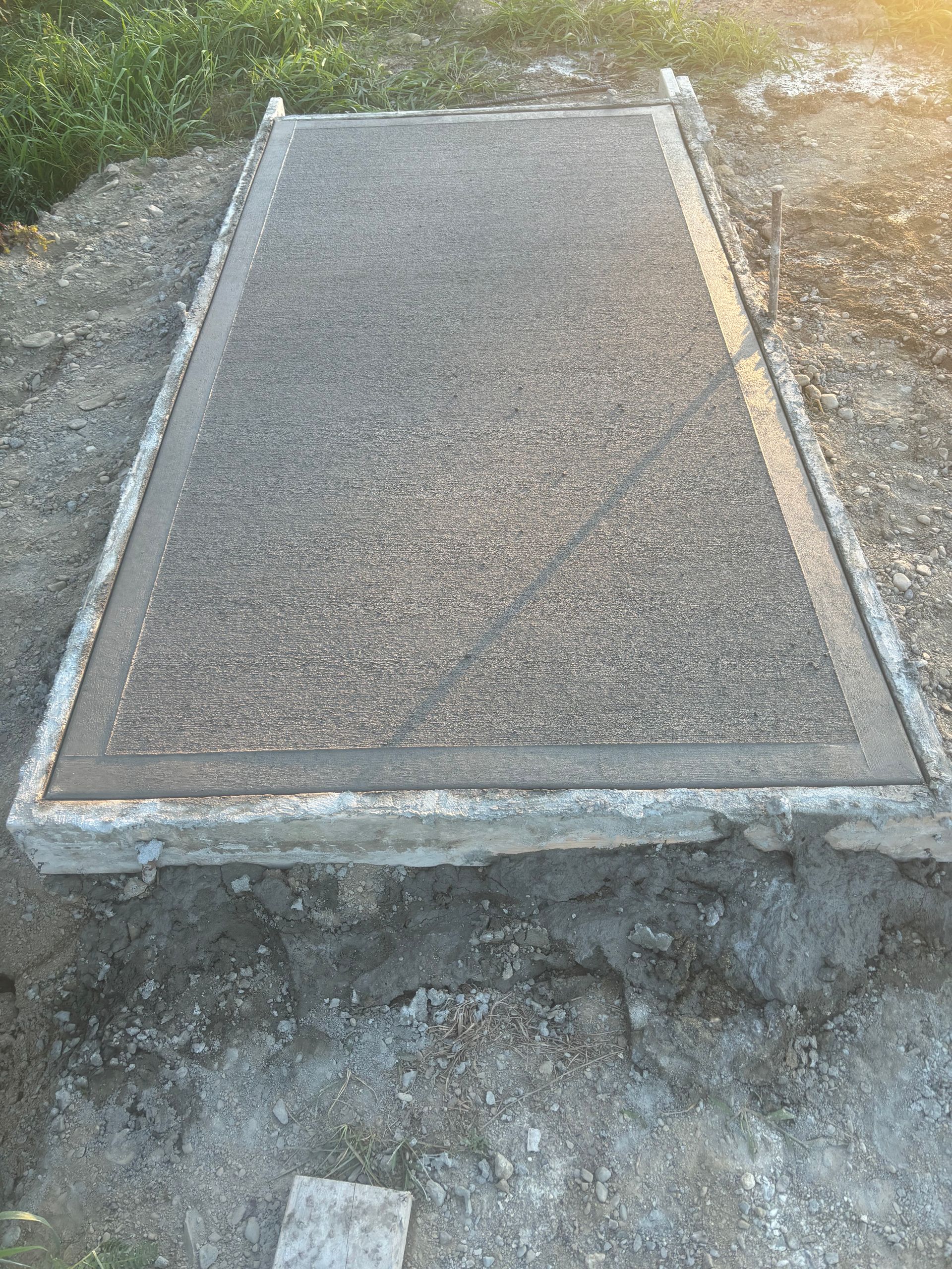 A large concrete slab is sitting on top of a dirt field.