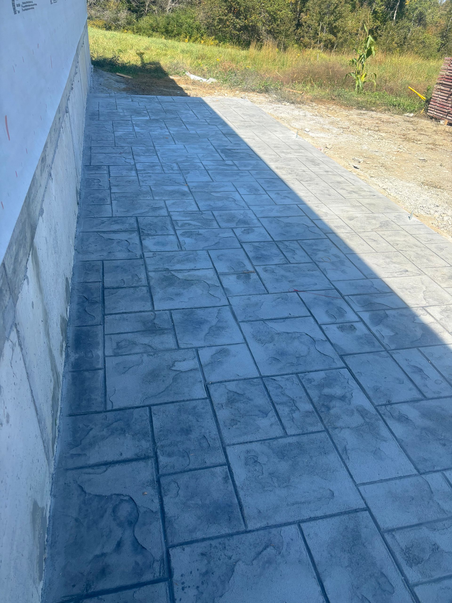 A concrete walkway with a shadow on the side of a building.