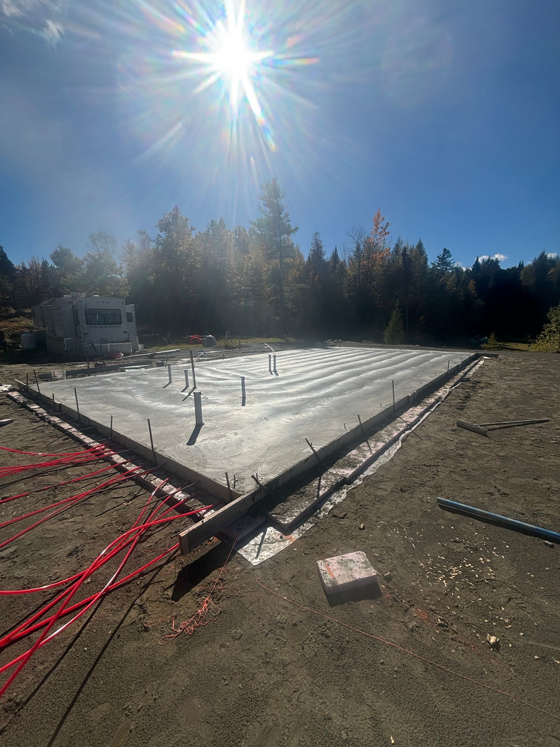 A concrete base for a house is being built on a sunny day.