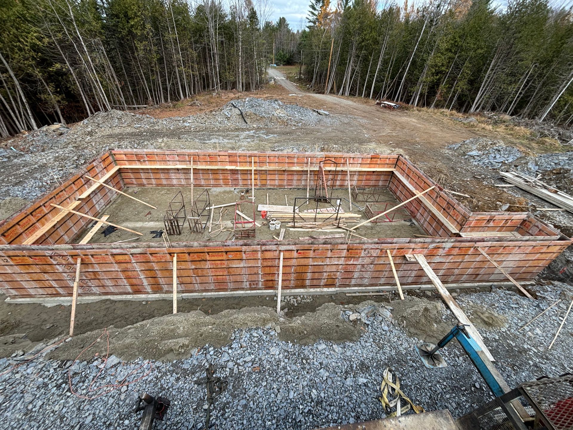 A large brick wall is being built in the middle of a gravel road.