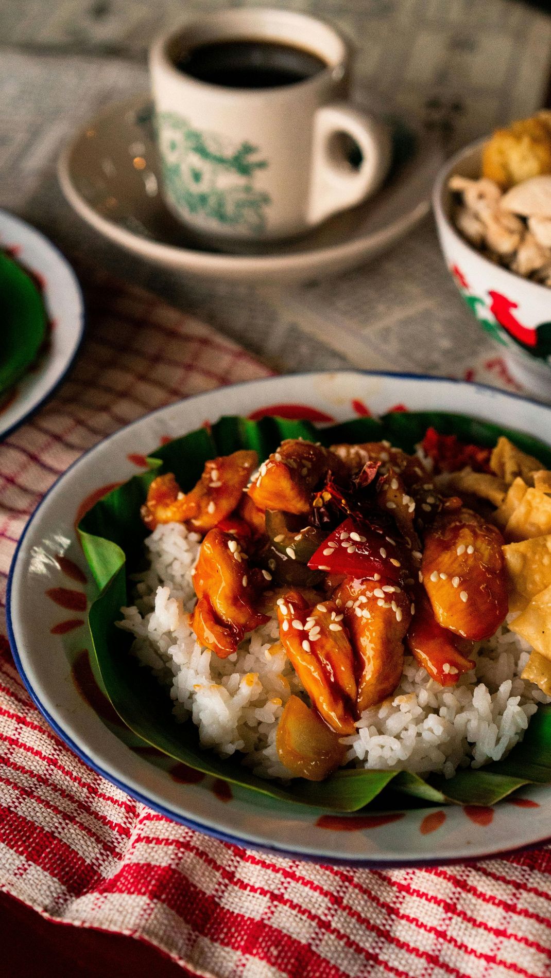 A plate of food with rice and meat on a table next to a cup of coffee.