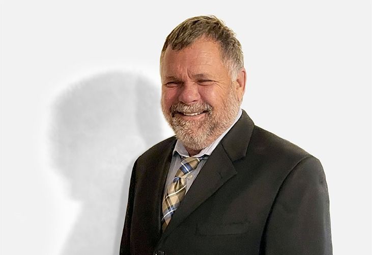 Smiling man in a dark suit against a white background