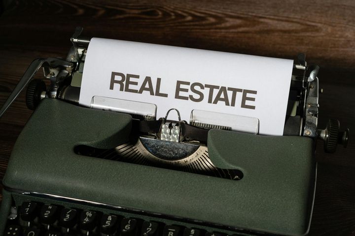 Typewriter with paper labeled “REAL ESTATE” on a dark wooden surface