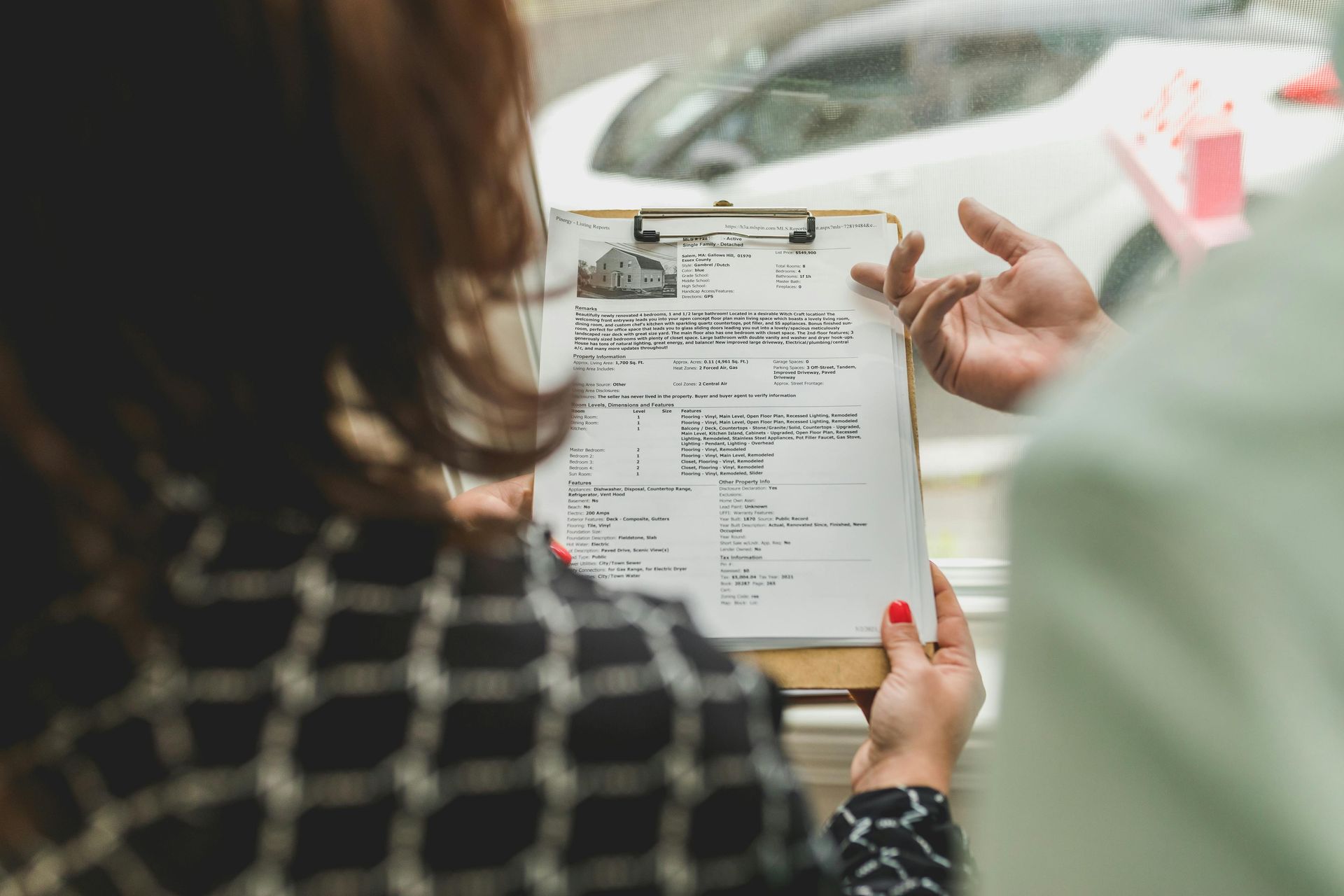 Person holding a clipboard while discussing a form with another person at a table