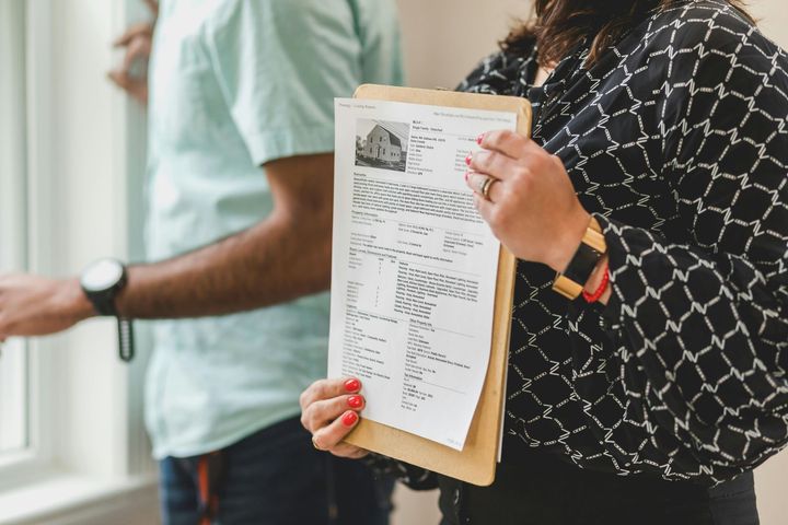 Two people holding clipboards, one reviewing a document in a bright office setting