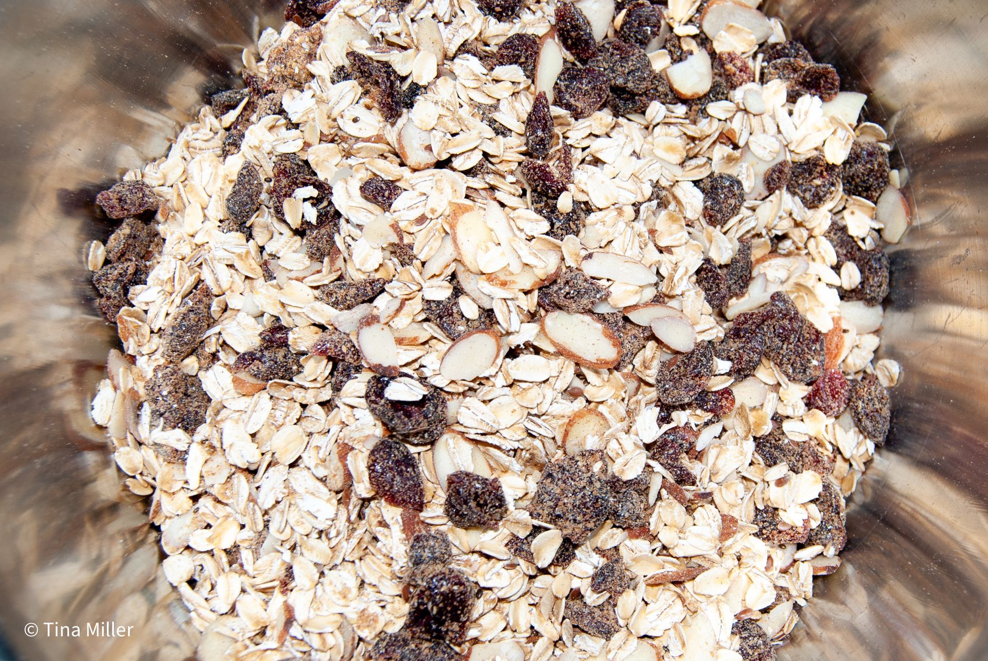 Dry old fashion oats mixed with dried cranberries in a large bowl.