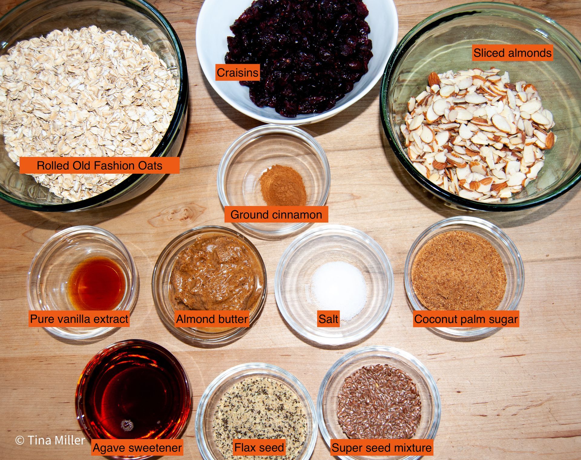 Ingredients of what is in crunchy homemade granola measured out in glass bowls and labled.