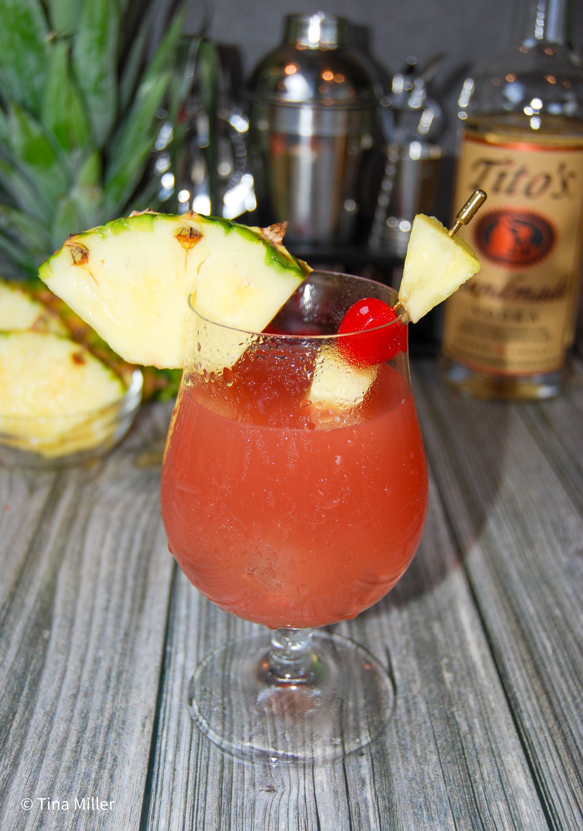 A Bay Breeze cocktail garnished with a pineapple slice maraschino cherry. 