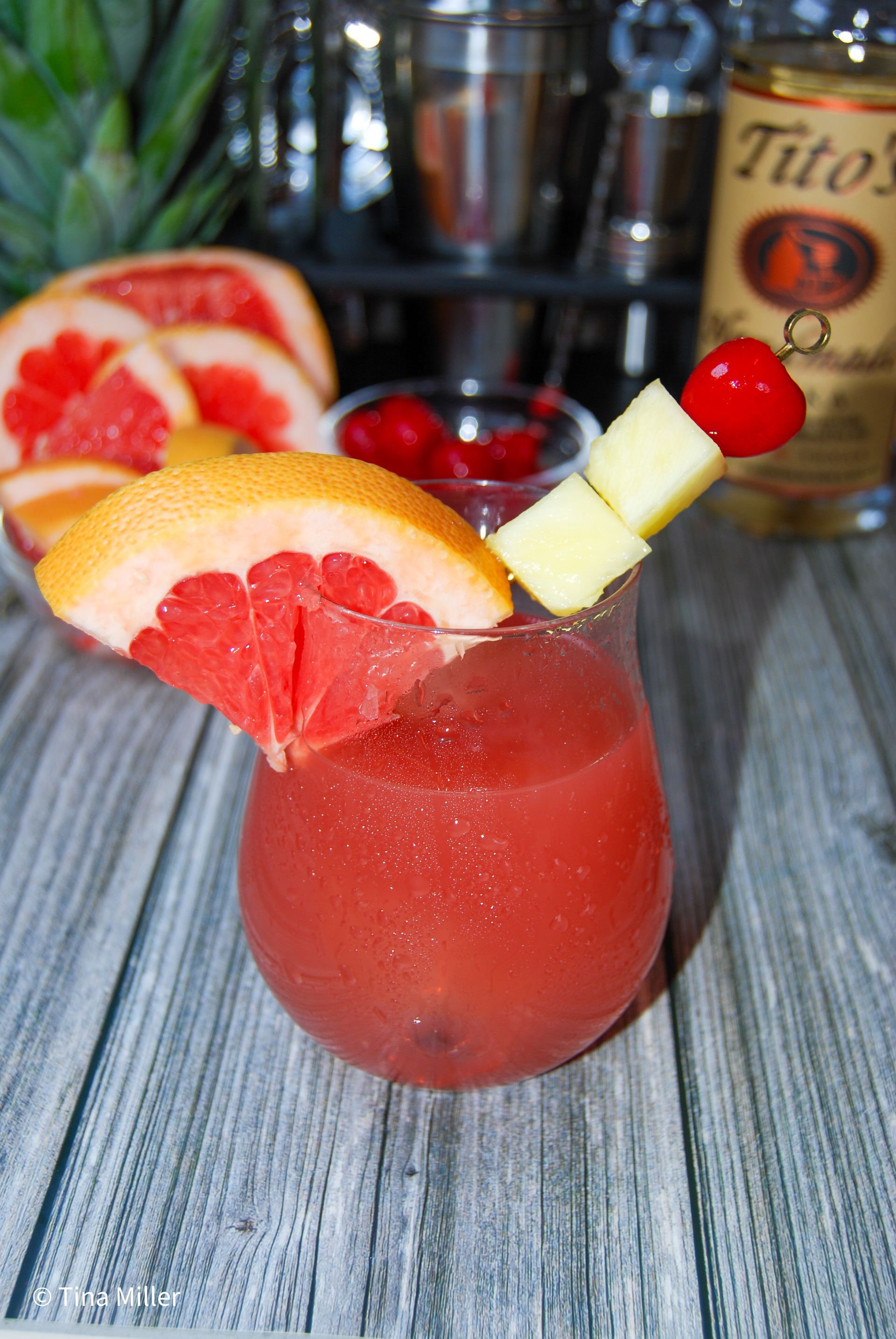 A Seabreeze cocktail drink with grapefruit, pineapple, and a maraschino, cherry for garnish.