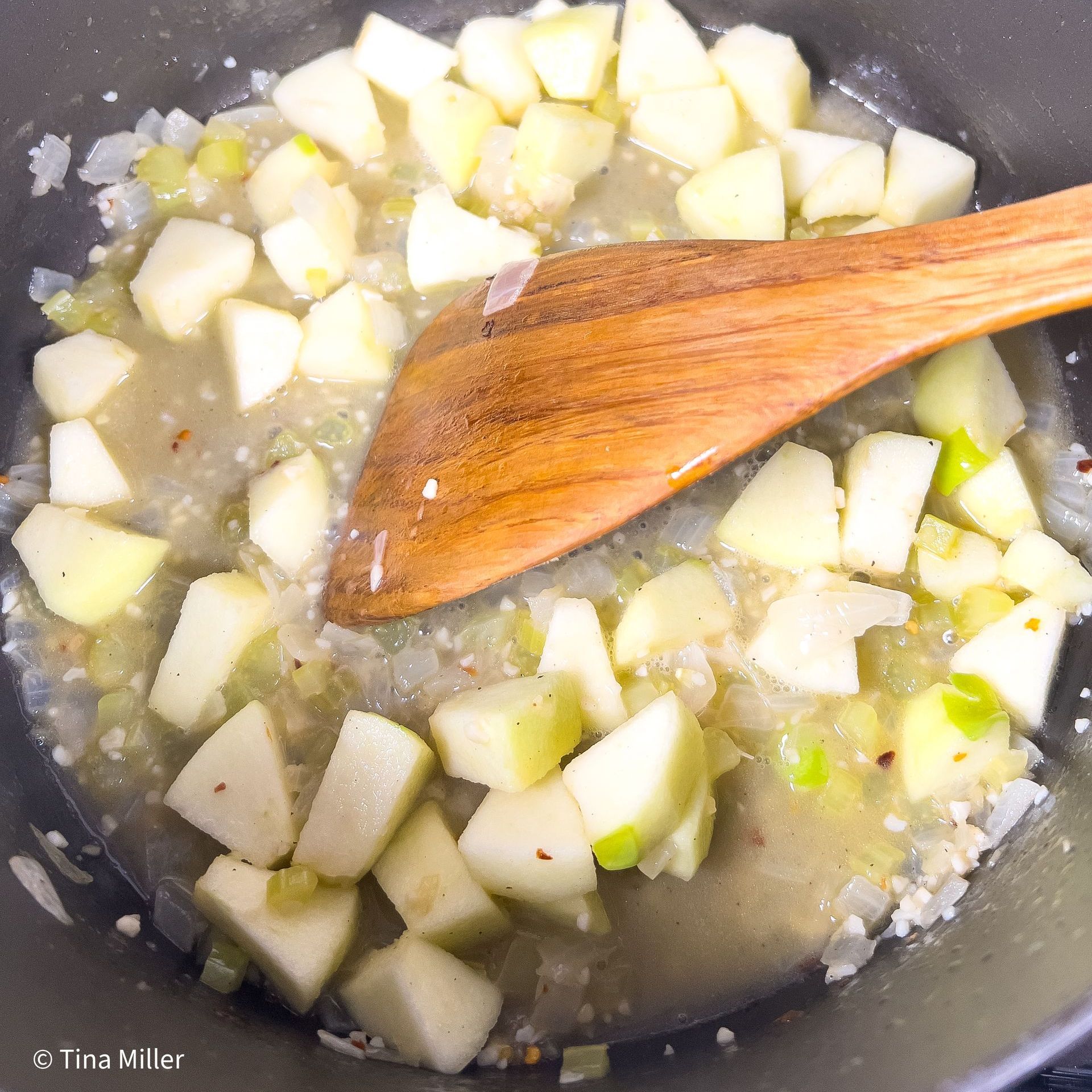 Dutch oven Granny Smith apples simmering in with white wine, sauteed onion, celery, garlic, ginger, and seasoning.