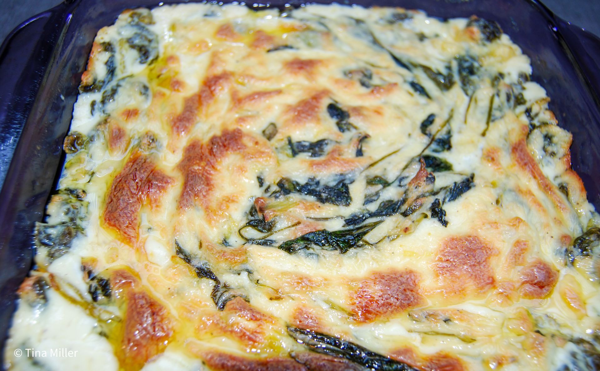 Spinach and artichoke dip into a 9x9 casserole dish after backing in the oven.
