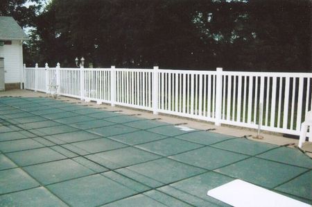 White railing along a green-tiled patio beside trees at dusk