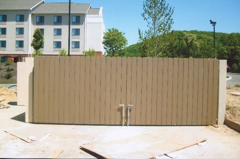 Beige wooden gate in a courtyard, with buildings and trees in the background