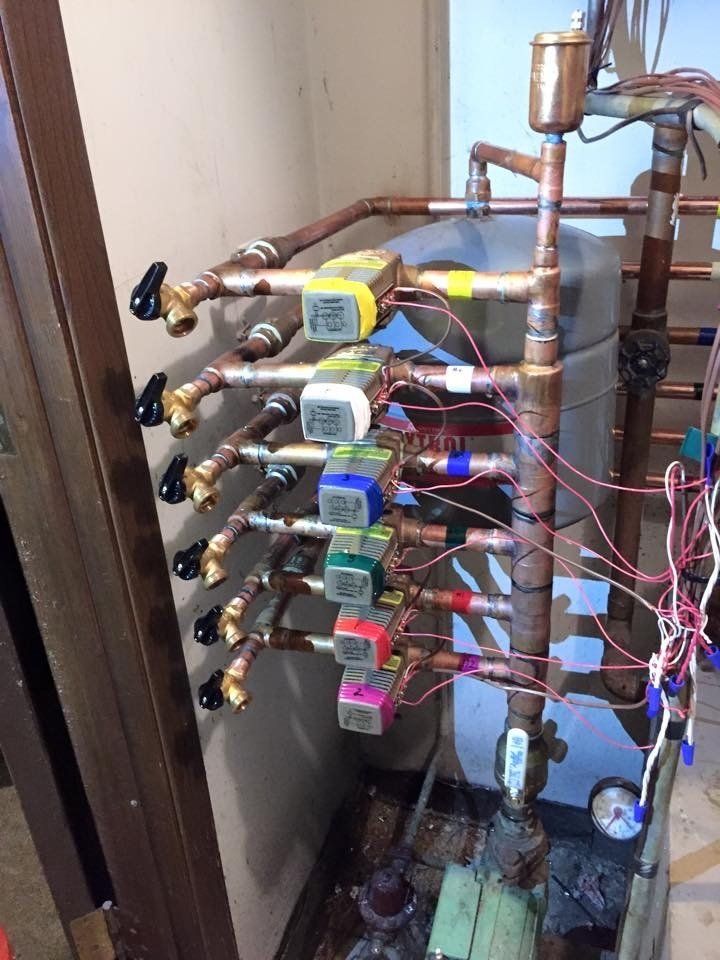 The image displays a radiant heat manifold system used for hydronic floor heating or similar applications.