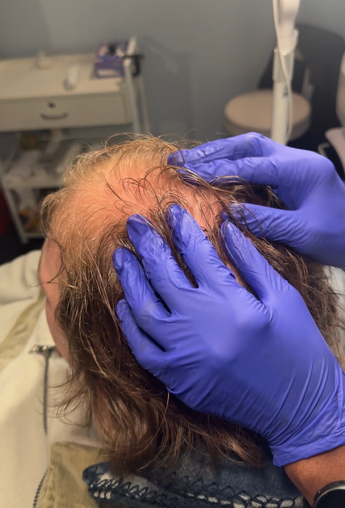 Medical professional in a red scrub top and purple cap holding several syringes while selecting items from a drawer.
