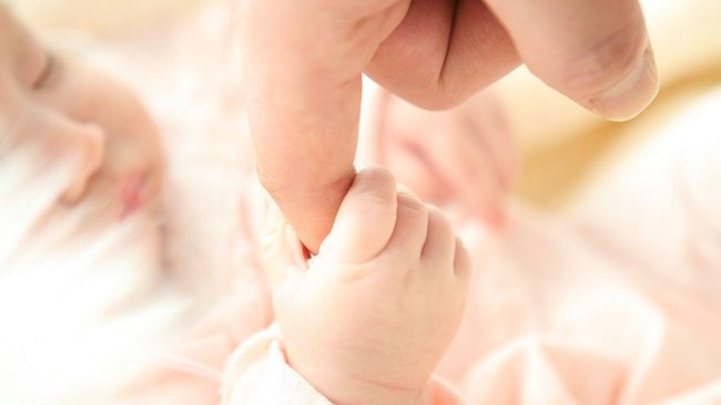 A close up of a person holding a baby 's hand.