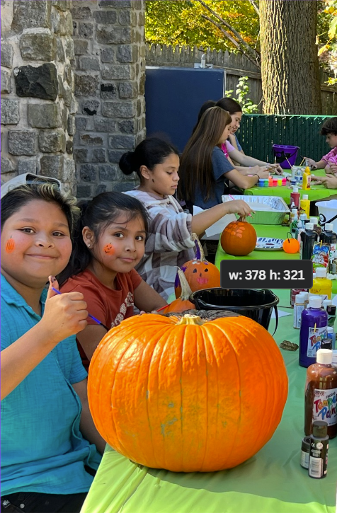 A group of children are sitting at a table carving pumpkins.