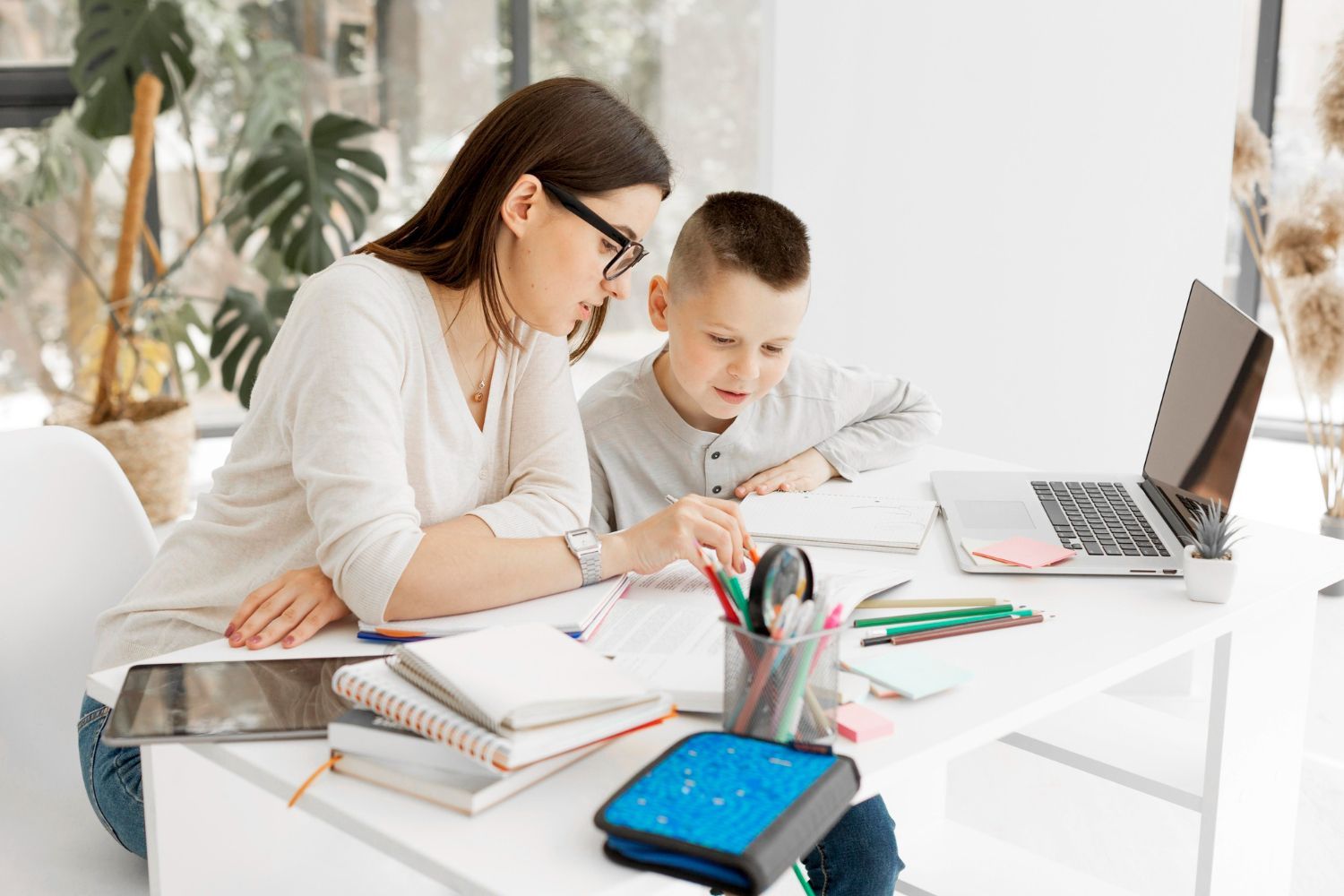 A woman is helping a young boy with his homework.