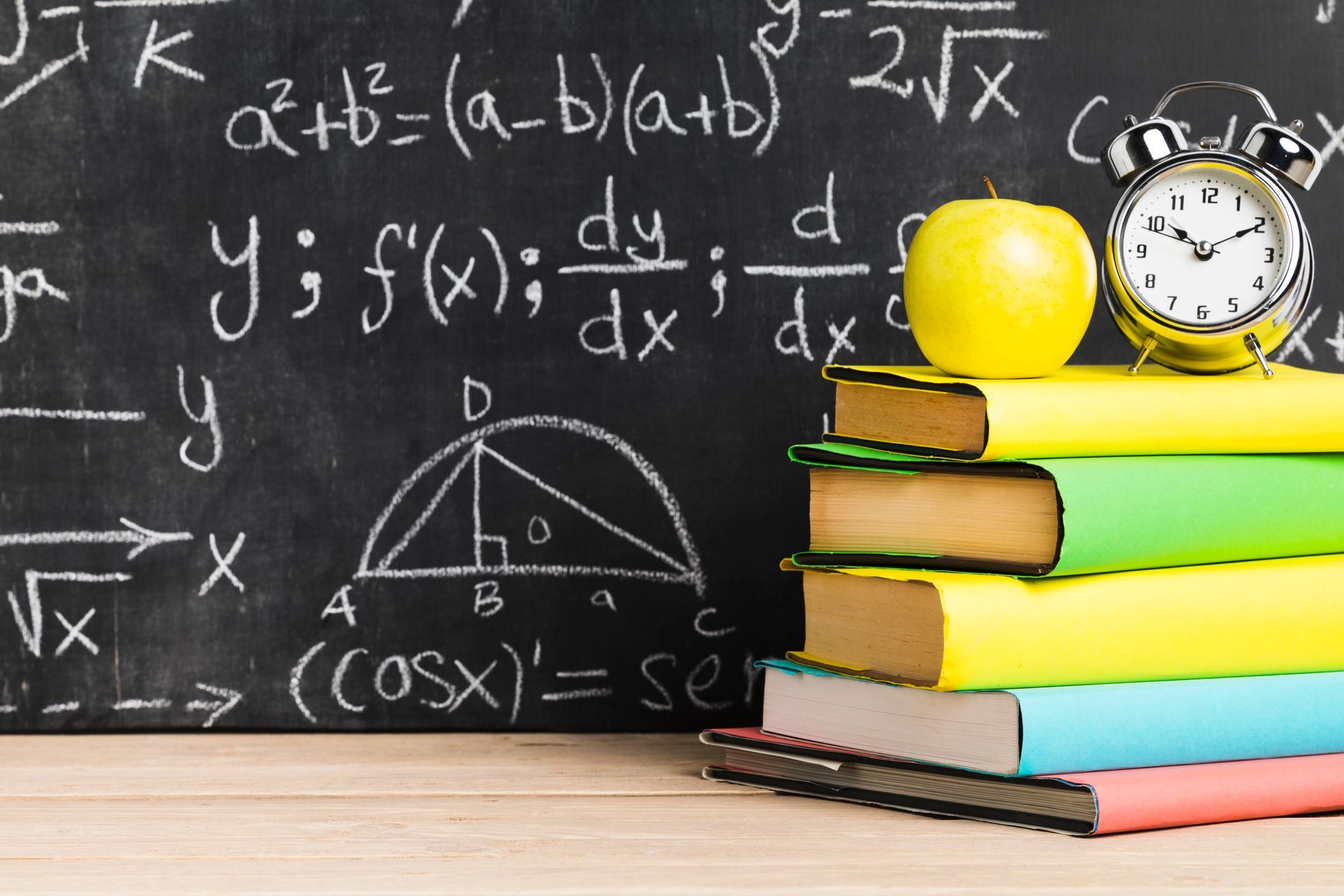 A stack of books sitting in front of a blackboard with math equations on it