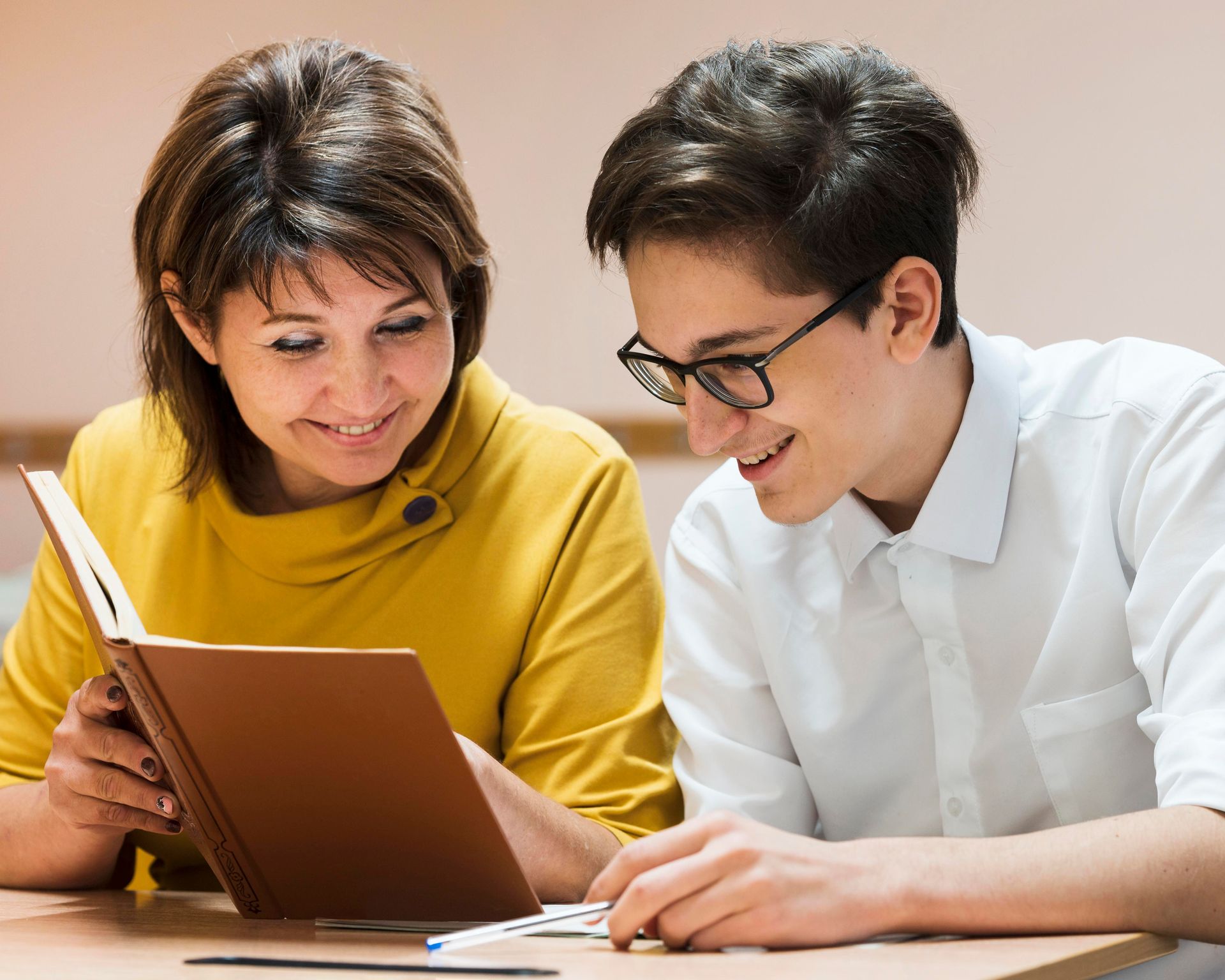 A man and a woman are sitting at a table reading a book.