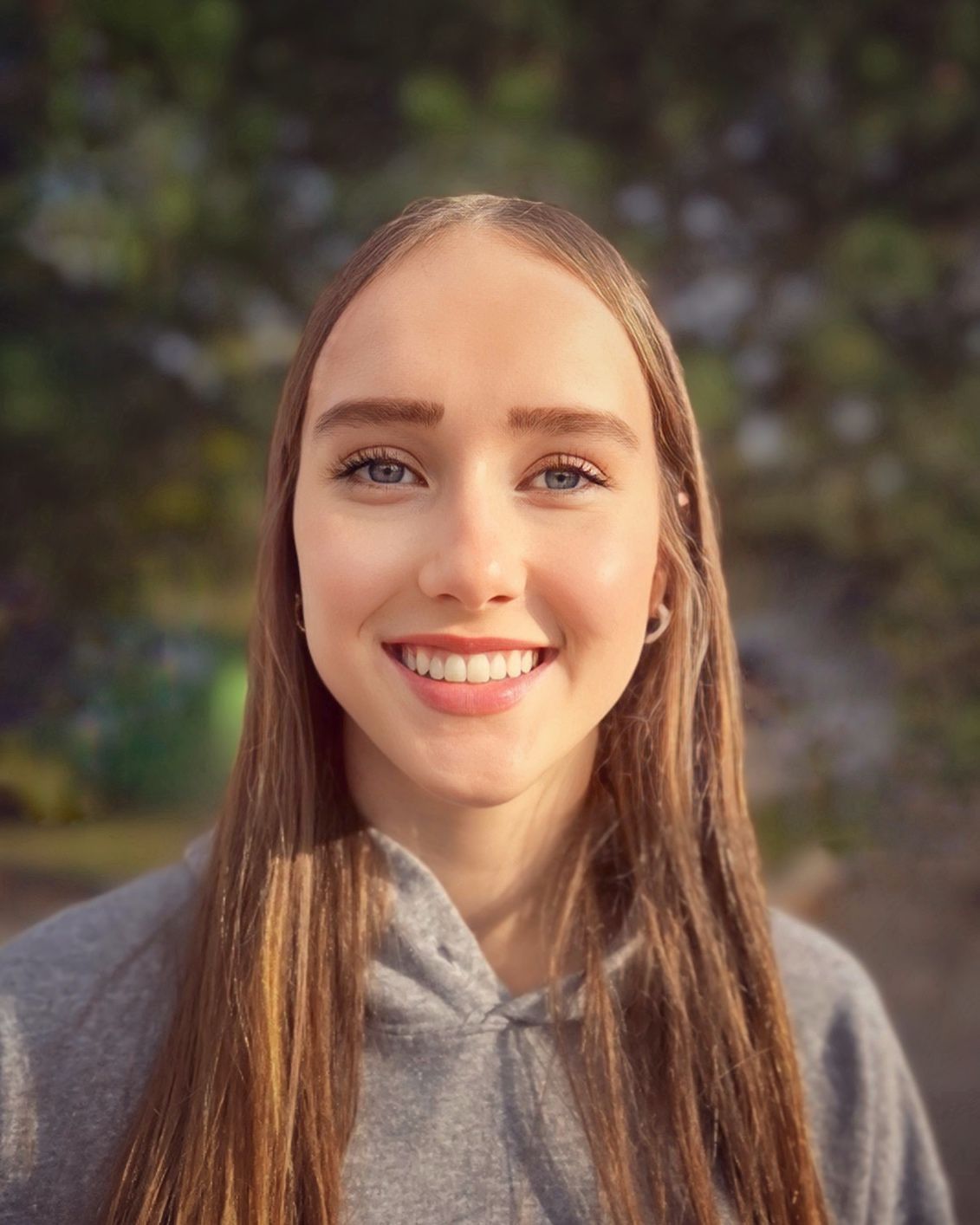 A young woman with long hair is smiling for the camera.