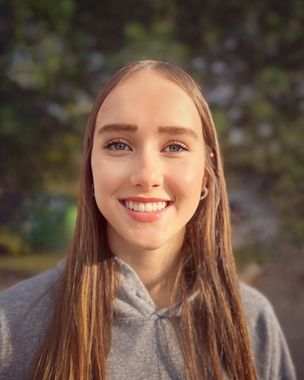 A woman wearing a black shirt and a necklace is smiling for the camera.