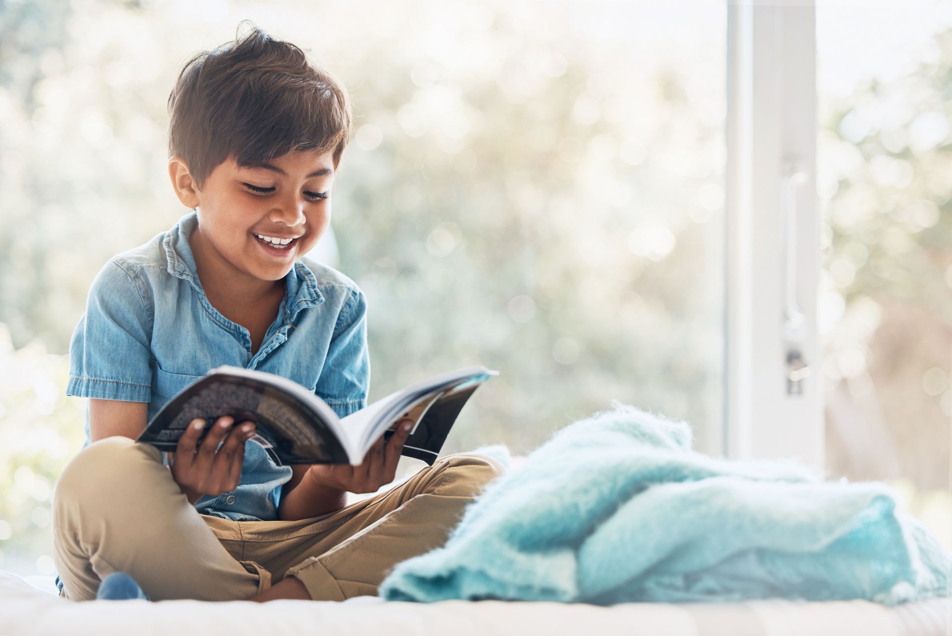 A young boy is sitting on the floor reading a book.