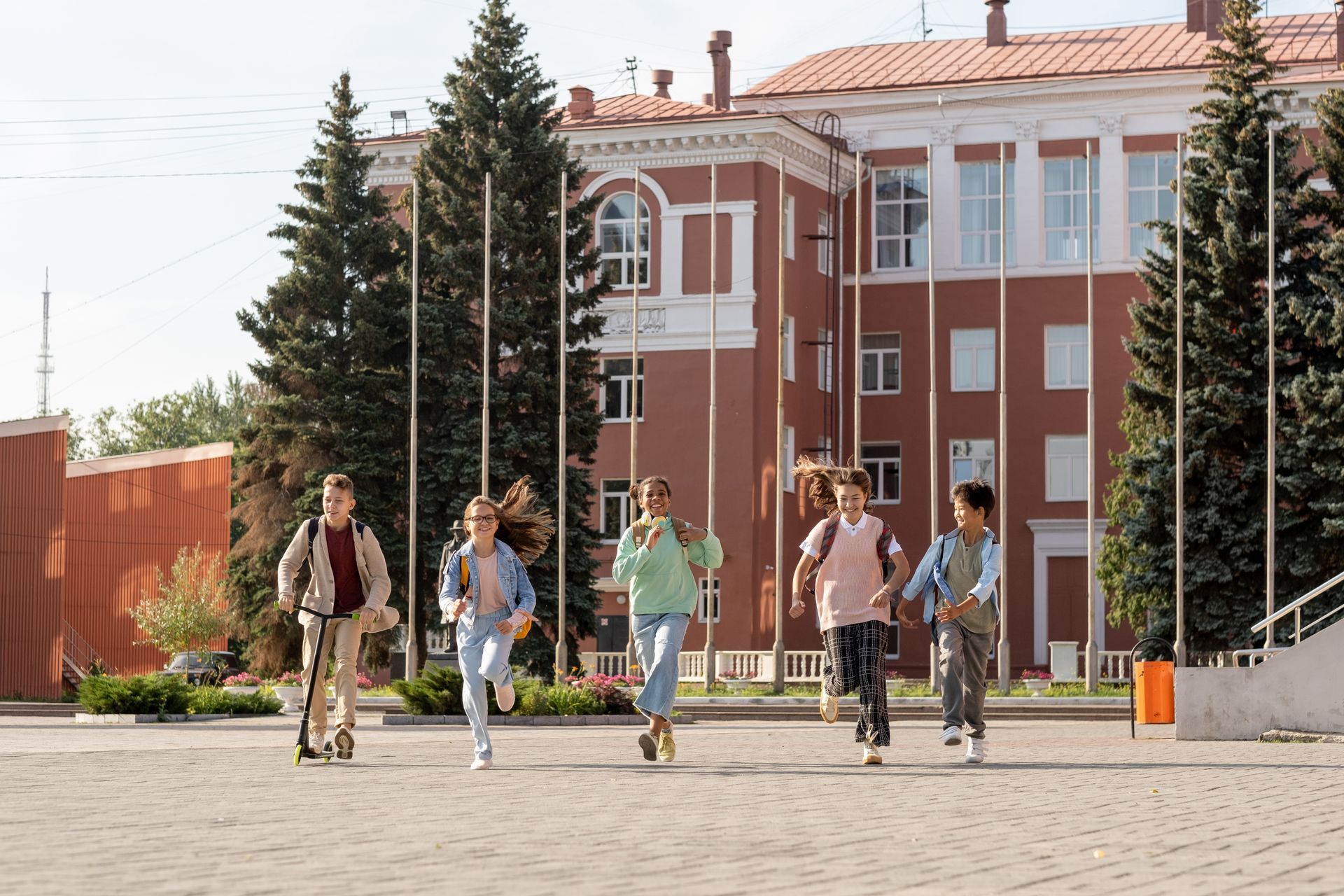 A group of children are riding scooters in front of a building.